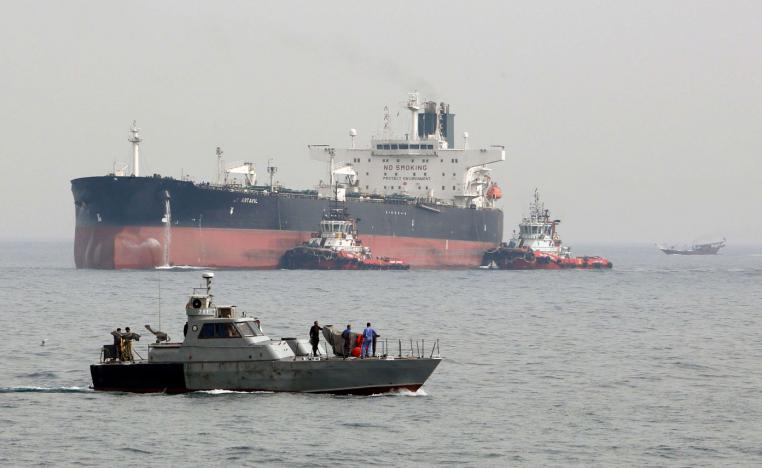 Iranian military speedboat patrols the waters as a tanker prepares to dock