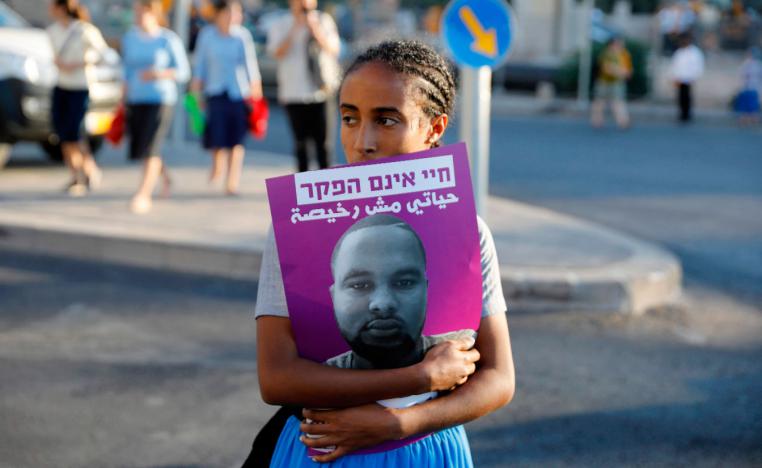 A woman holds a poster of Solomon Teka, who was shot dead by an off-duty police officer