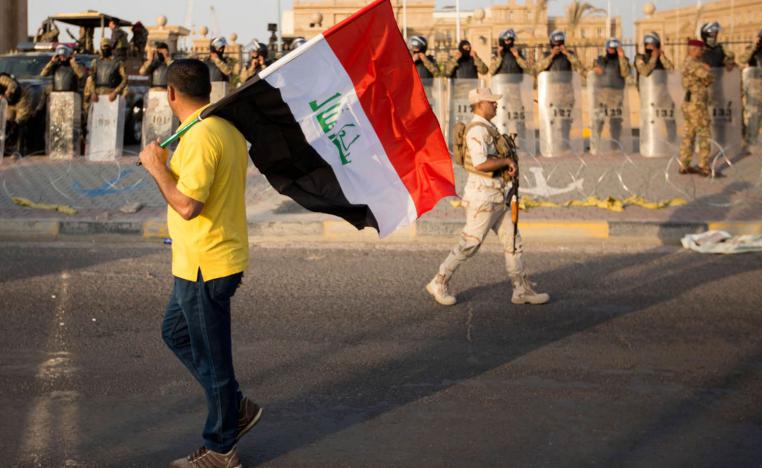 متظاهر عراقي يحمل علما أمام مبنى مجلس محافظة البصرة