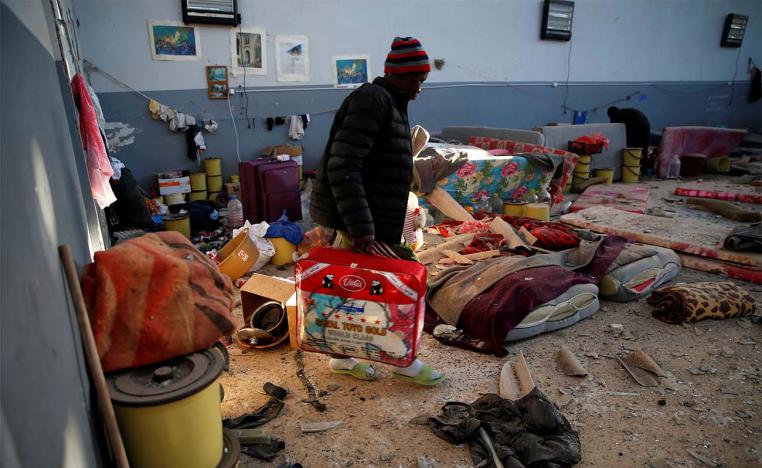 A migrant carries his belongings at a detention centre for mainly African migrants in Tajoura