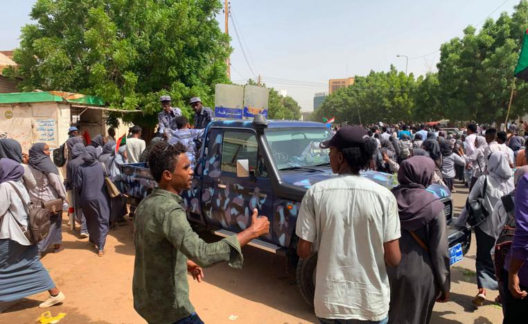 Sudanese protesters march past security forces' vehicle during a demonstration commemorating protesters killed