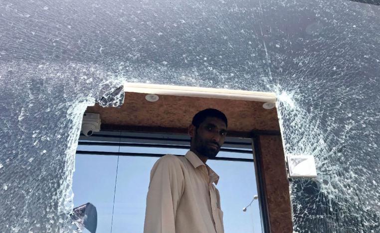 A parking employee looks at a damaged glass window at Saudi Arabia's Abha airport