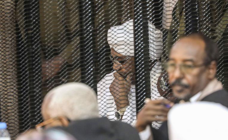 Sudan's autocratic former President Omar al-Bashir sits in a cage during his trial on corruption and money laundering charges in Khartoum