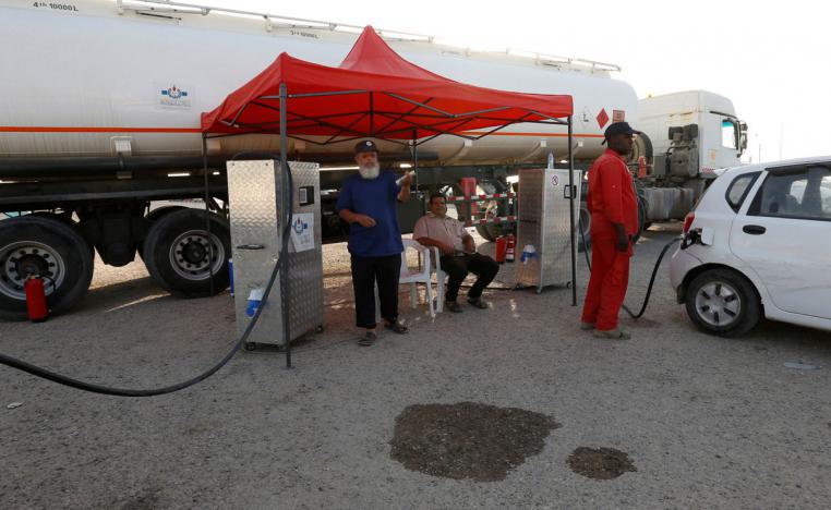 An employee of the state fuel distribution company, Brega, fills a car in Tripoli