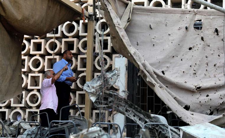 Egyptian investigators are seen in front of the damaged facade of the National Cancer Institute after the fire from last weekend's blast