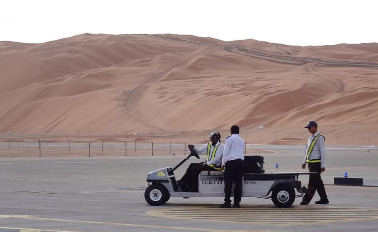 Aramco staff members stand on the tarmac at the Saudi Aramco airport