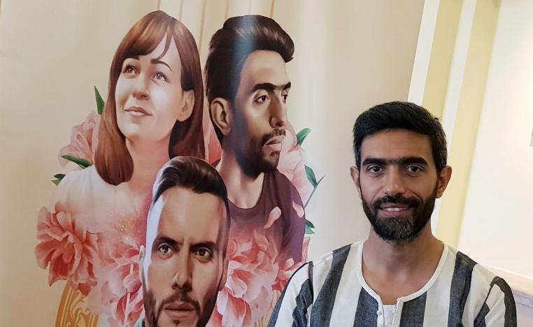 بطل الفيلم عمرو عابد يقف بجانب الملصق الدعائي لفيلمه في مهرجان الجونة السينمائي