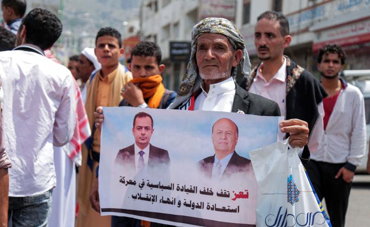A demonstrator marches with a sign declaring support for Yemen's government