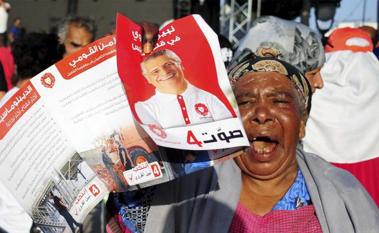 A supporter of jailed Tunisian presidential candidate Nabil Karoui shows his portrait during a gathering in Tunis