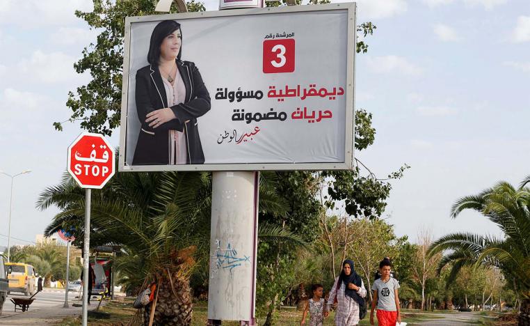 People walk past an election campaign billboard depicting presidential candidate, Abir Moussi, in Tunis