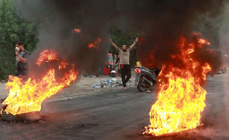 Anti-government protesters set fires and close a street during a demonstration in Baghdad