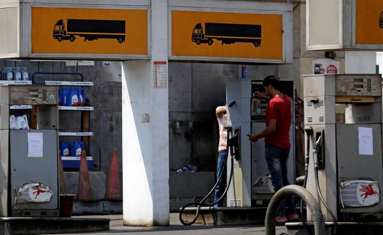 Employees at a petrol station work on a fuel dispenser input a new price of fuel in Cairo