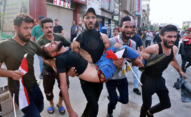 An injured protester is carried after reacting to tear gas fired by security forces during a protest in Tahrir Square