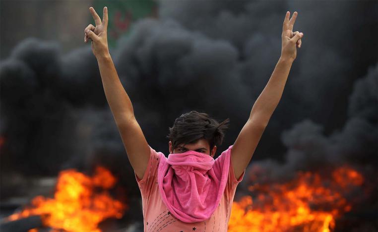 An Iraqi protester flashes the v-sign during a demonstration against state corruption, failing public services and unemployment in Baghdad