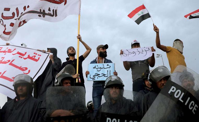 raqi policemen stand in front of demonstrators during a protest over corruption, lack of jobs, and poor services, in Kerbala