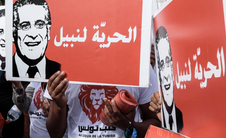 Supporters of the jailed Tunisian media magnate and presidential candidate Nabil Karoui hold placards