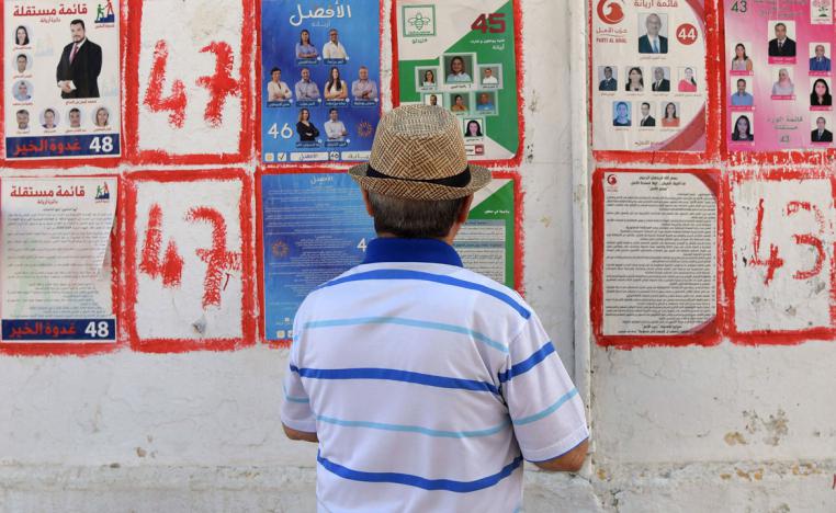 A Tunisian man looks at posters of legislatives' candidates in the capital Tunis