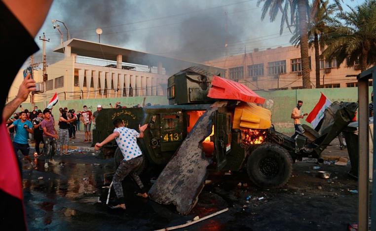 Anti-government protesters burn an armoured vehicle belonging to the Federal Police Rapid Response Forces during a protest in Baghdad