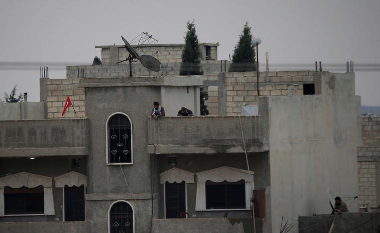 Turkey-backed Syrian rebel fighters stand on a building in the Syrian town of Ras al Ain