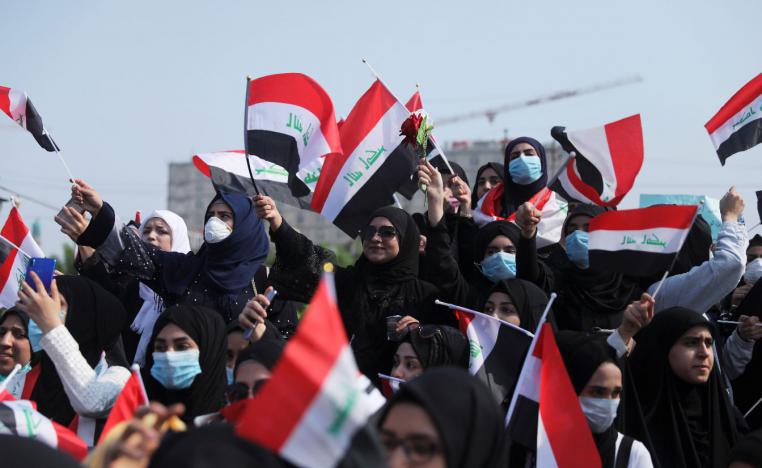 Universities students hold the Iraqi flag as they take part in a protest over corruption, lack of jobs, and poor services