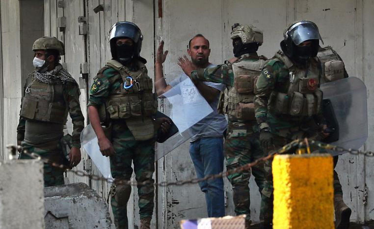 Iraqi security forces arrest a protester in downtown Baghdad