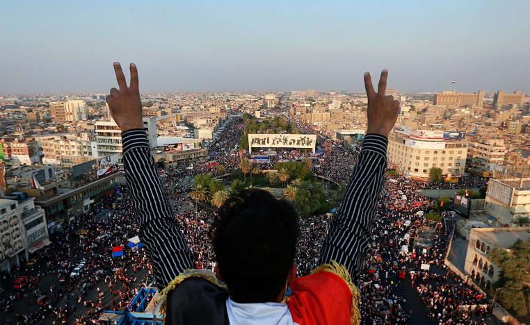 A protester flashes the victory sign while anti-government protesters gather in Tahrir Square during ongoing protests in Baghdad