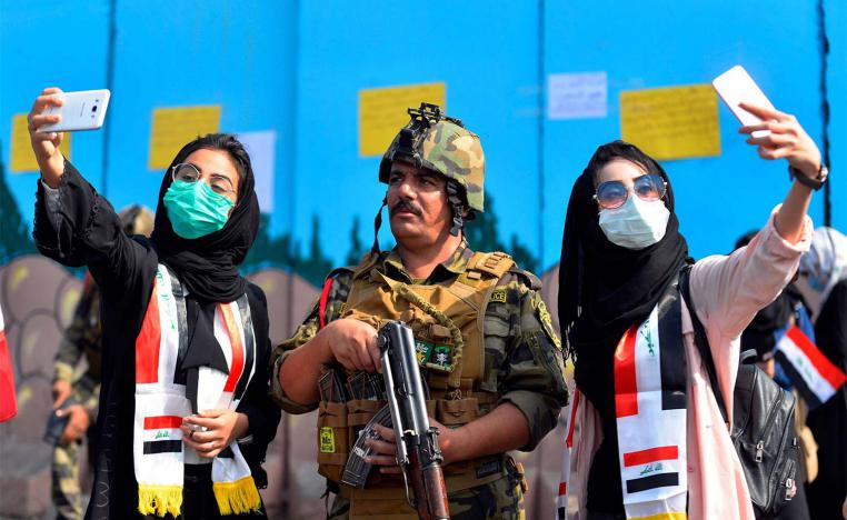 Iraqi students pose for selfies with a member of the security forces during ongoing anti-government protests in Diwaniyah