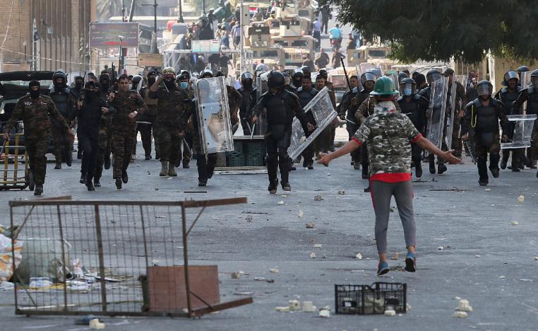 Iraqi anti-riot police try to prevent anti-government protesters from crossing the al- Shuhada (Martyrs) bridge