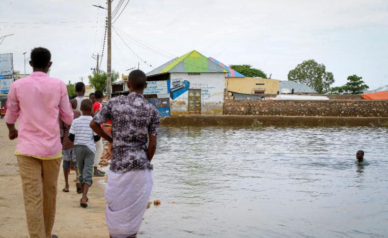 In this photo taken Monday, Nov. 4, 2019, a child swims in the floodwaters as others walk past, in the town of Beledweyne, in central Somalia