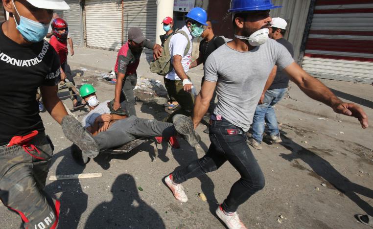 Iraqi demonstrators evacuate a wounded man on the Martyrs' Bridge in Baghdad