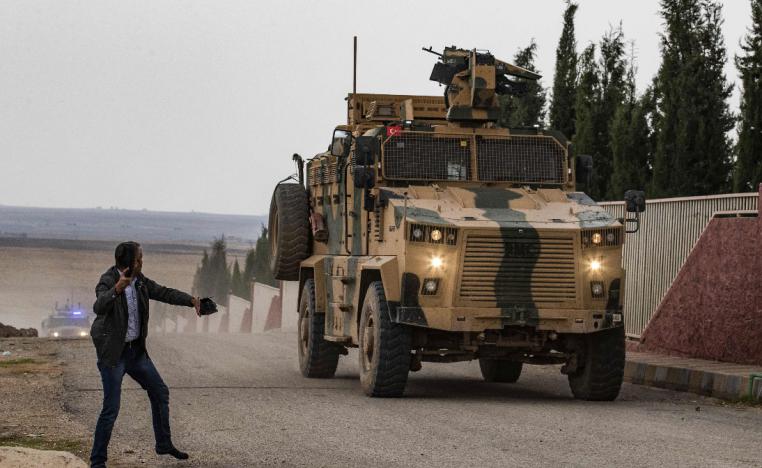  A man tosses his shoes at a Turkish military vehicle on patrol in the countryside of the town of Darbasiyah