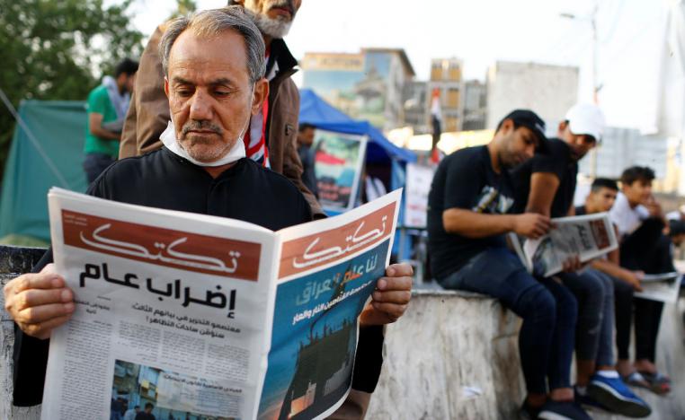 An Iraqi demonstrator reads Tuktuk newspaper during the ongoing anti-government protests in Baghdad