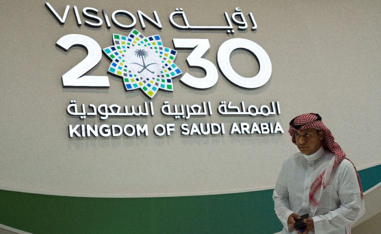 A Saudi man walks past a "Vision 2030" display