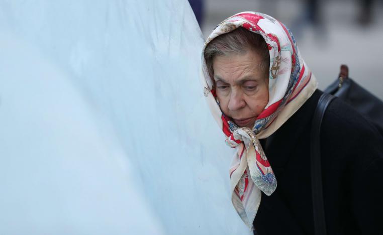 امرأة تضع رأسها على كتلة جليد خلال معرض فني بلندن للتوعية بآثار التغير المناخي