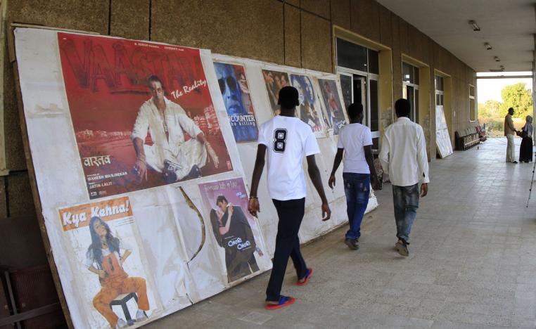 رجال سودانيون يمشون عبر ملصقات إعلانية لأفلام في سينما أم درمان في الخرطوم 