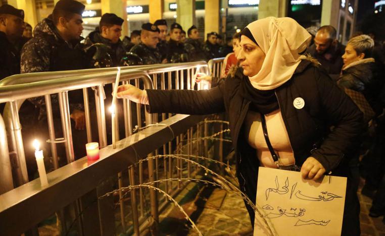لبنانية تشعل شمعة أمام قوات الأمن على حاجز وسط بيروت