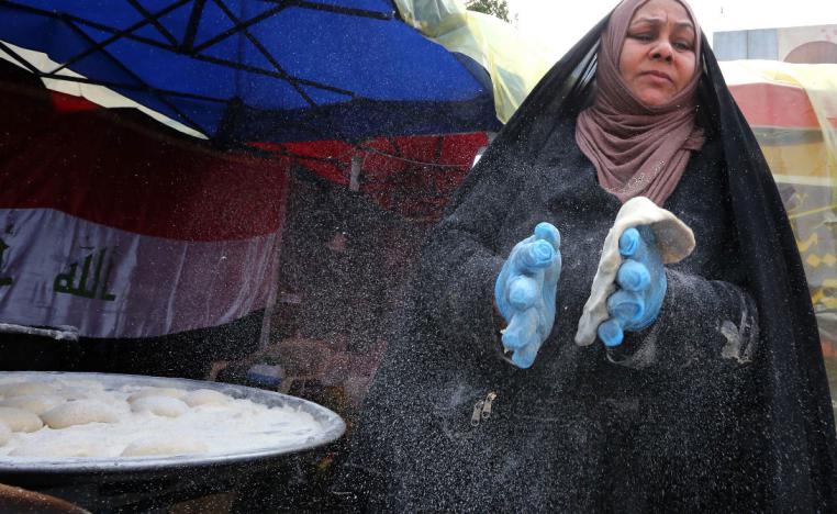 An Iraqi woman prepares traditional bread on the sidelines of ongoing anti-government protests at Tahrir square