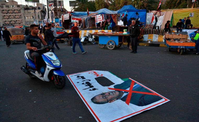 A poster with a defaced photo of Qusay al-Suhail with  Arabic that reads, "one of the leaders of the destruction," seen in Tahrir Square, Baghdad