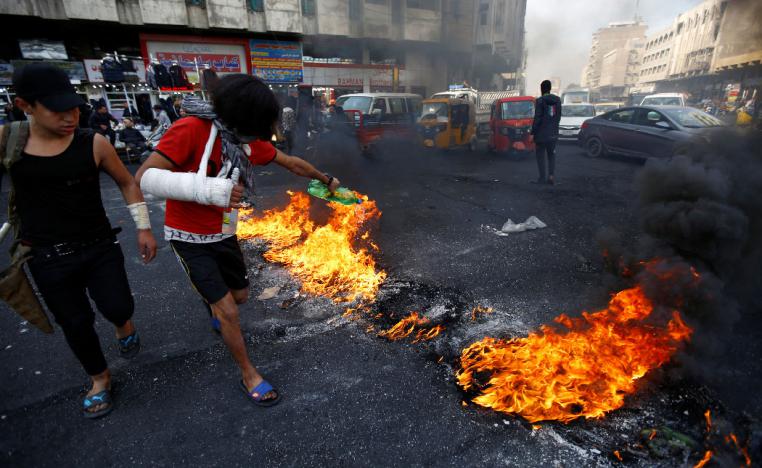An Iraqi demonstrator sets tires on fire during ongoing anti-government protests in Baghdad