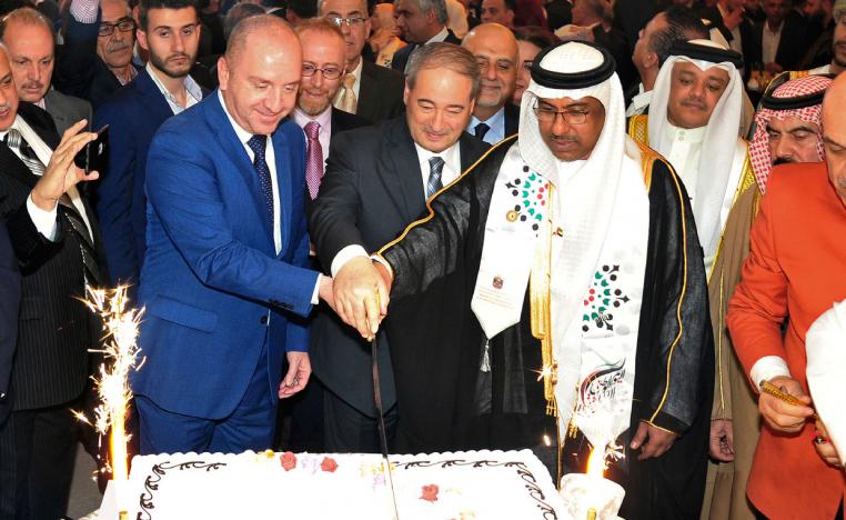 United Arab Emirates Charge d'affaires Abdul-Hakim Naimi, center right, cuts a cake with Syria's Deputy Foreign Minister Faisal Mekdad