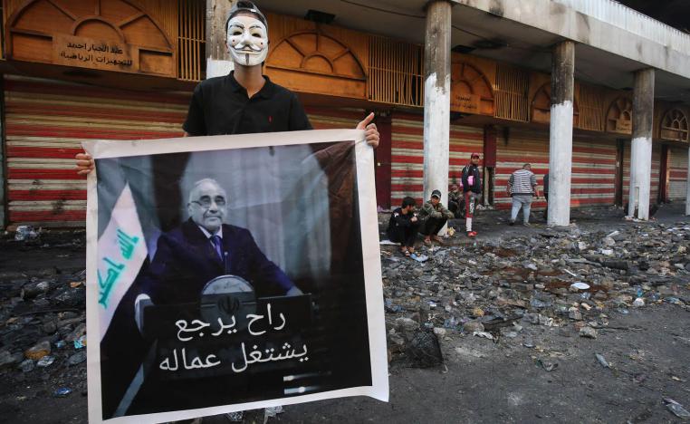 متظاهر يرفع صورة تسخر من رئيس الوزراء العراقي المستقيل عادل عبدالمهدي