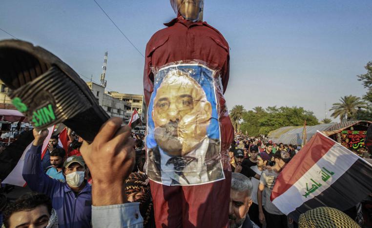 عراقيون يضربون صورة لرئيس الوزراء العراقي عادل عبدالمهدي