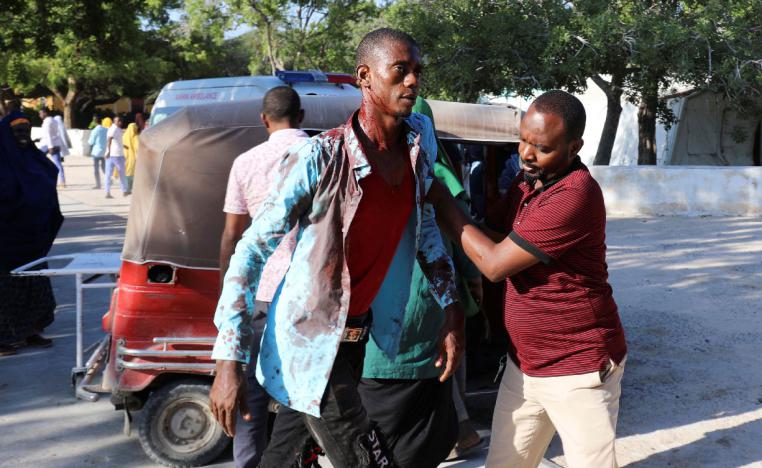 A man assists a civilian injured at the scene of a car bomb explosion at a checkpoint in Mogadishu
