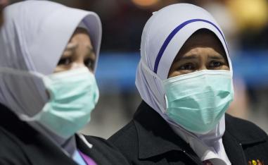مسؤولتان عن الصحة ترتديان أقنعة الوجه في مطار كوالالمبور الدولي 