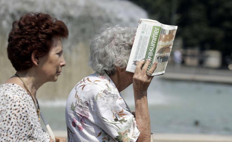 سيدة مسنة تغطي وجهها من أشعة الشمس الحارقة بصحيفة في ميلانو بإيطاليا في صيف 2019