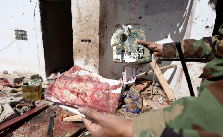 A Yemeni soldier shows a destroyed copy of the Quran at the site of a Huthi missile attack