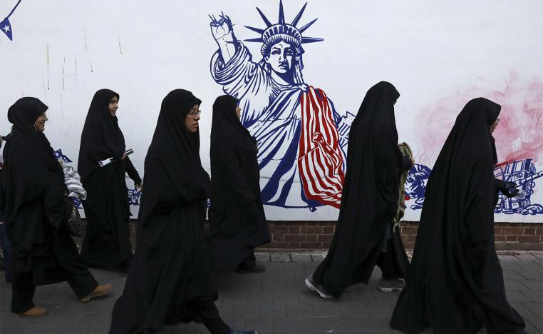 Iranian women passing a satirical drawing of the Statue of Liberty painted on the wall of the former US Embassy in Tehran