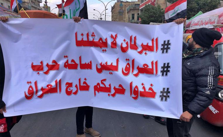 Protesters hold a banner with Arabic that reads, "Parliament does not represent me, Iraq is not a battlefield, and Take your war outside Iraq" during a sit-in at Tahrir Square in Baghdad