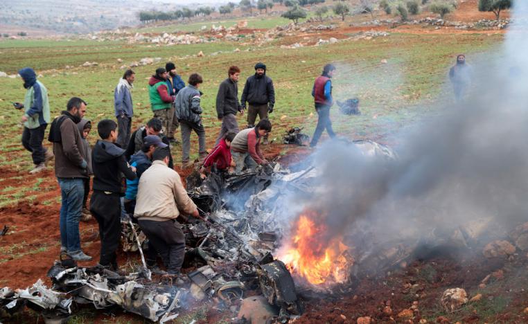 People inspect the wreckage of a military helicopter of the Syrian government forces that was downed over the western Aleppo Province