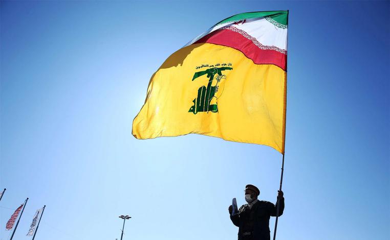 An Iranian carries the Iranian and Hezbollah flags during the commemoration of the 41st anniversary of the Islamic revolution in Tehran